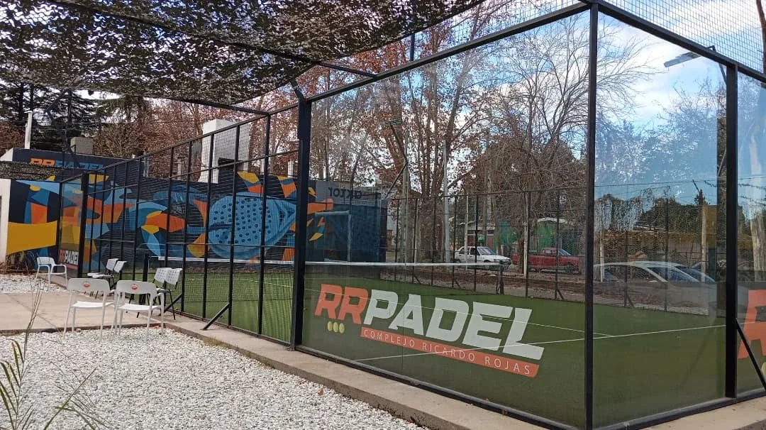 Cancha exterior de RR con el nombre del complejo en el vallado y mural de pádel